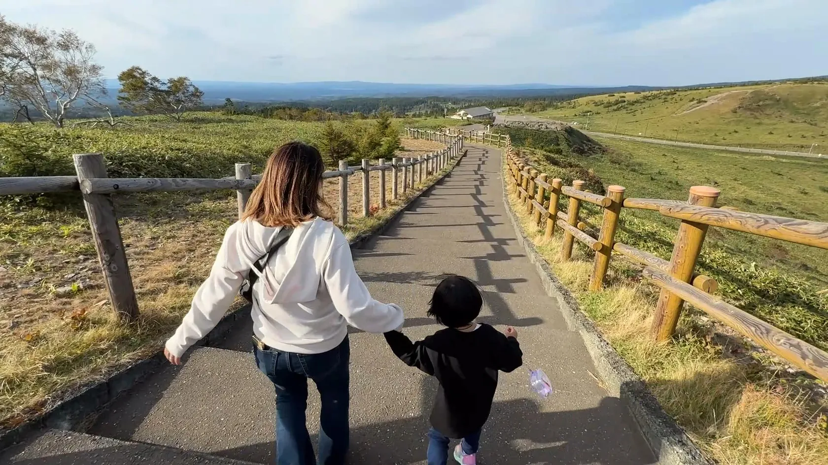 旅先の道を手をつないで歩く親子の後ろ姿